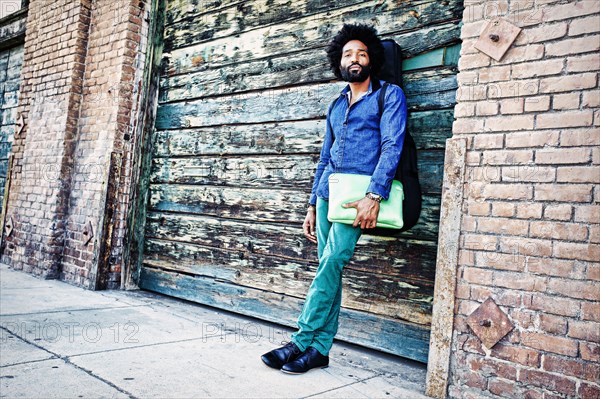 Mixed race musician carrying laptop outdoors