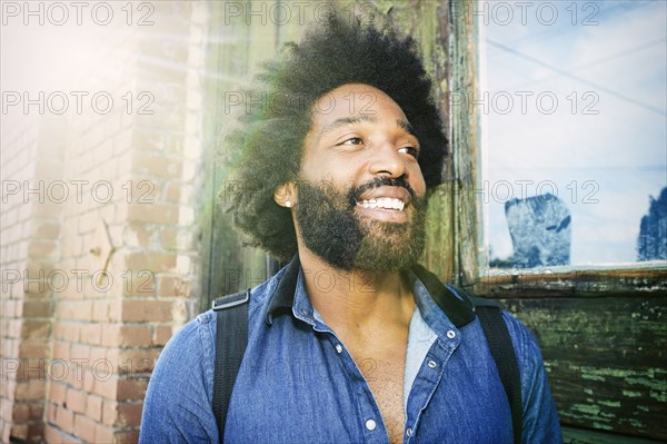 Mixed race musician carrying guitar outdoors