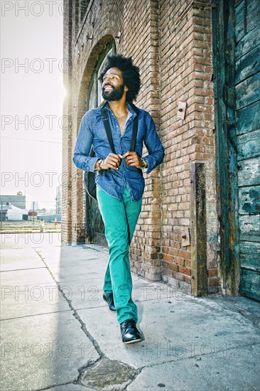 Mixed race musician carrying guitar outdoors