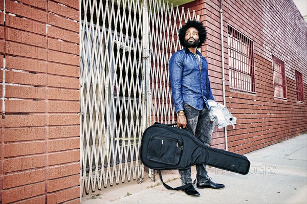 Mixed race man carrying guitar outdoors