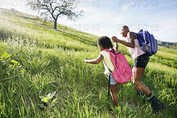 Black mother and daughter walking on rural hillside