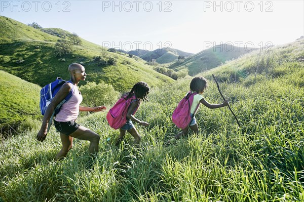 Black mother and daughters walking on rural hillside