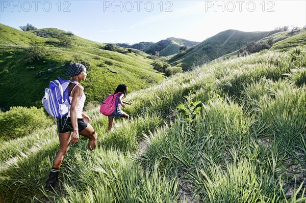 Black mother and daughter walking on rural hillside