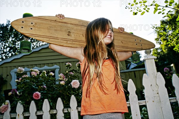 Caucasian girl carrying skateboard outdoors