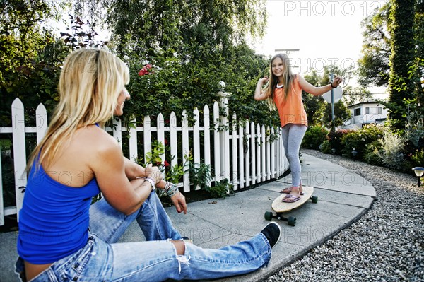 Caucasian mother watching daughter ride skateboard