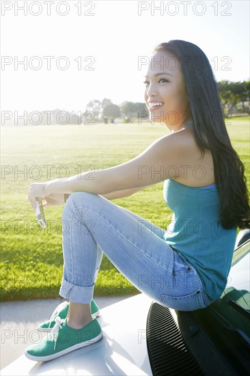 Asian woman sitting on car