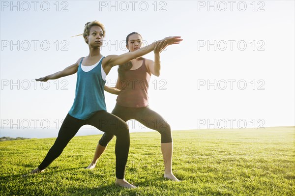 Teacher helping student practice yoga outdoors