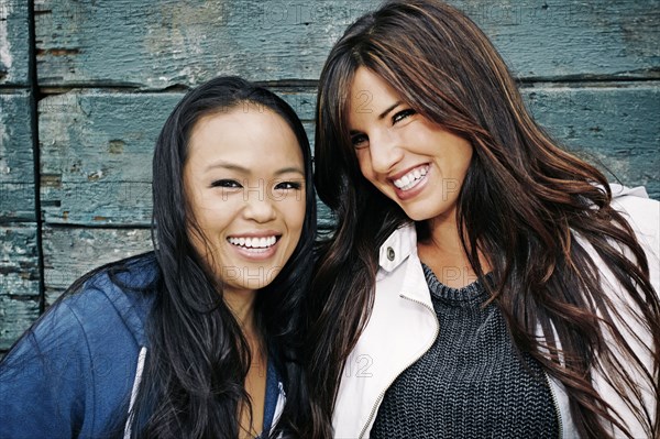 Women smiling at wooden wall