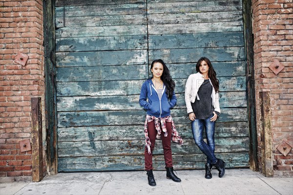 Women standing at wooden wall