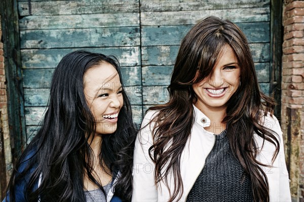 Women laughing at wooden wall