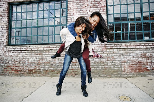 Woman carrying friend piggyback