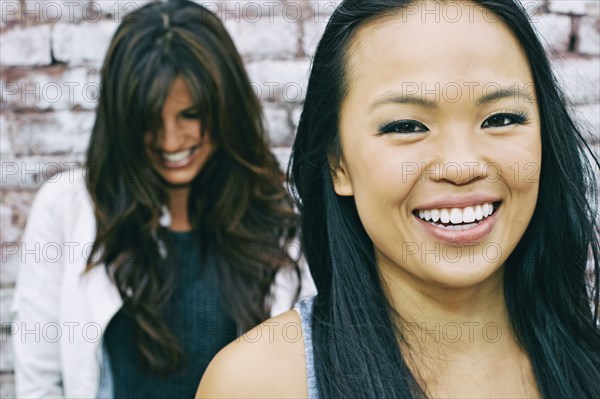 Women smiling at brick wall