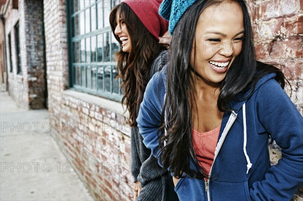 Women laughing in front of brick wall