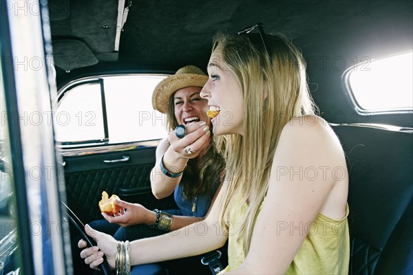 Woman feeding friend in vintage car