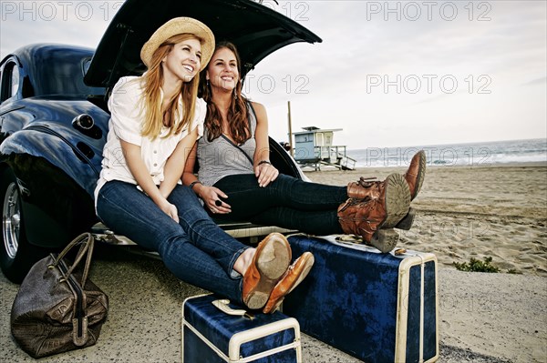 Women with luggage and vintage car on beach