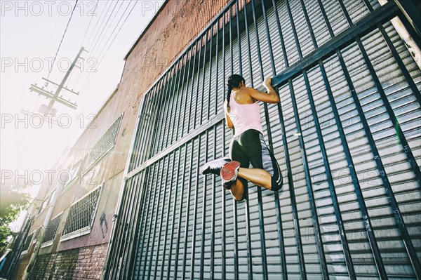 Mixed race woman doing pull-ups on gate