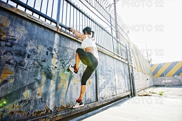 Mixed race woman climbing gate