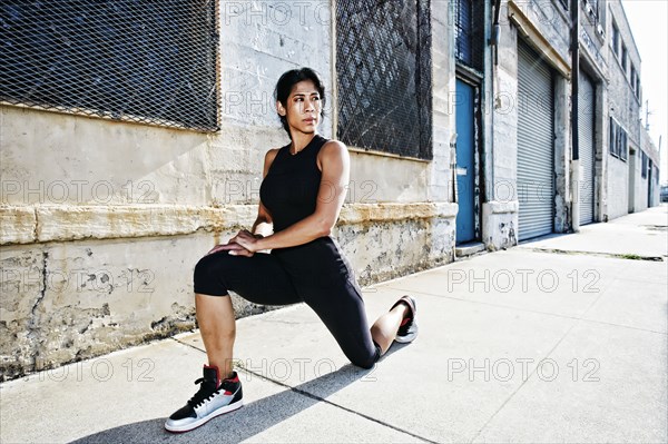 Mixed race woman stretching on sidewalk