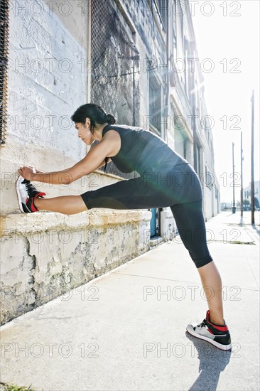 Mixed race woman stretching on sidewalk