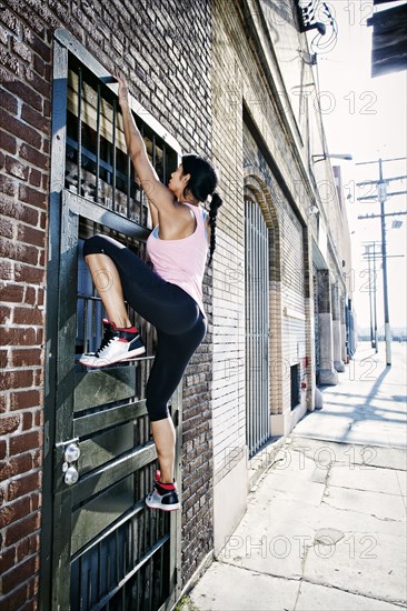 Mixed race woman climbing gate