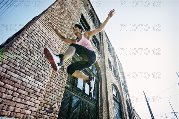 Mixed race woman jumping outdoors