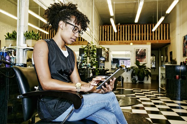 Mixed race hairstylist using digital tablet in salon