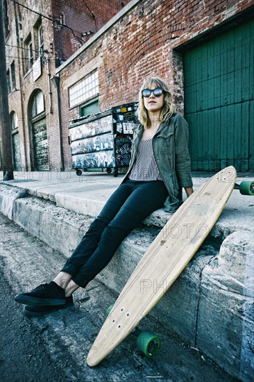 Caucasian woman sitting with skateboard