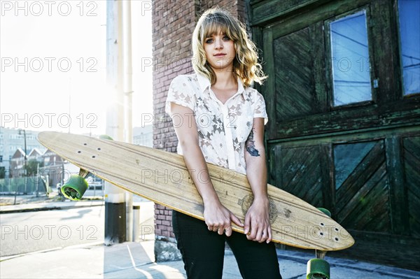 Caucasian woman carrying skateboard