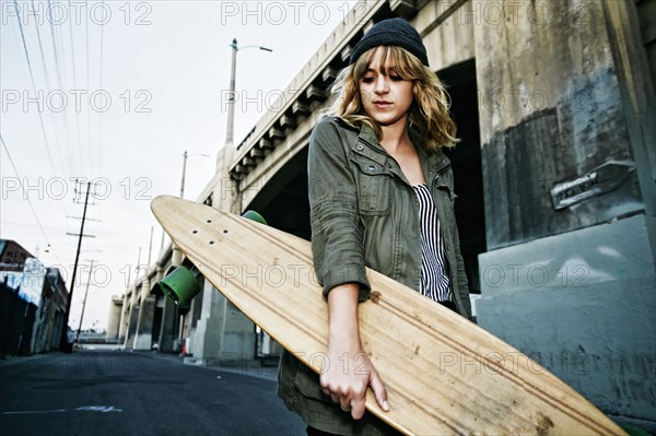 Caucasian woman carrying skateboard outdoors