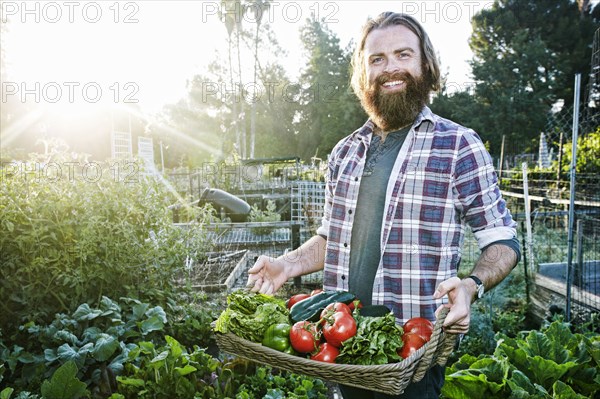 Caucasian man holding basket of vegetables in garden