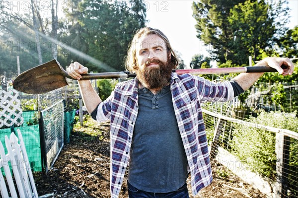 Caucasian man holding shovel in garden