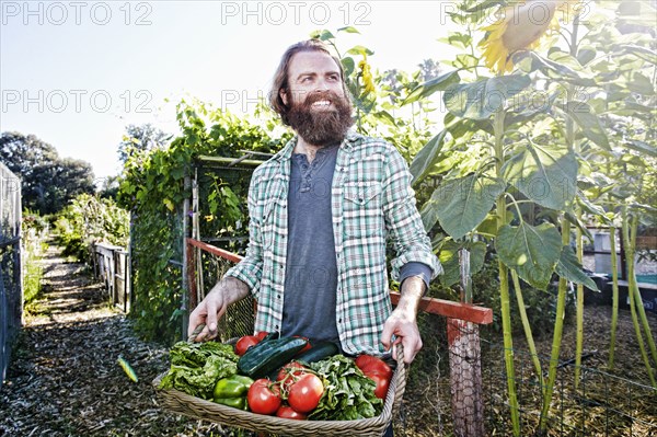 Caucasian man holding basket of vegetables in garden