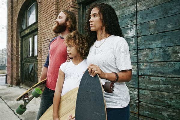 Family holding skateboards outdoors