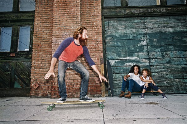 Family riding skateboards on sidewalk