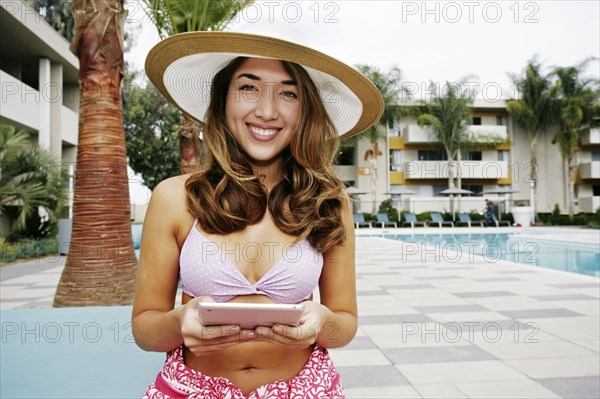 Hispanic woman using digital tablet at swimming pool