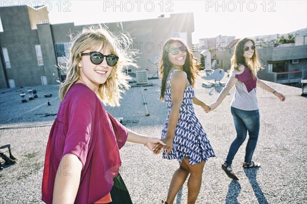 Women holding hands on urban rooftop