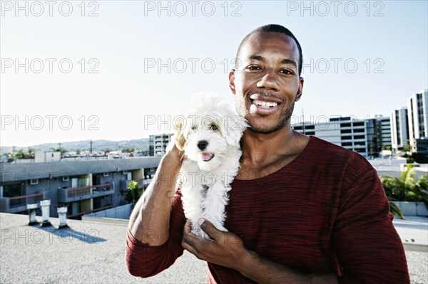 African American man holding dog on urban rooftop
