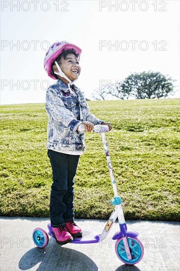 Black girl wearing helmet on scooter