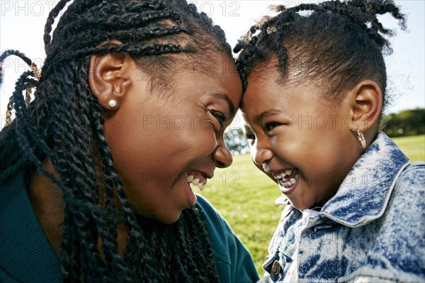 Black mother and daughter smiling outdoors