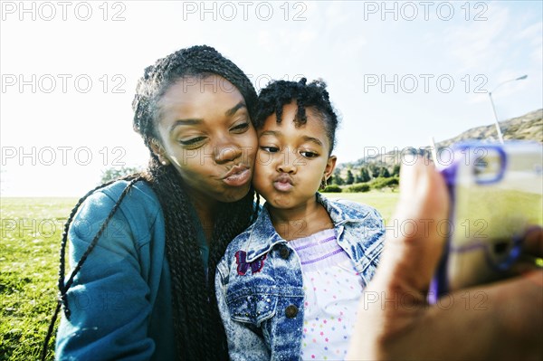 Black mother and daughter taking selfie outdoors