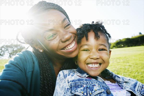 Black mother and daughter smiling outdoors