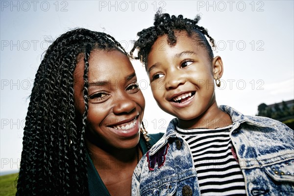 Black mother and daughter smiling outdoors