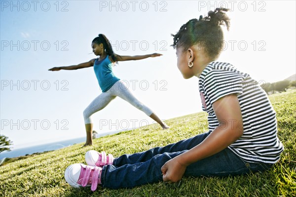 Black girl watching mother practicing yoga