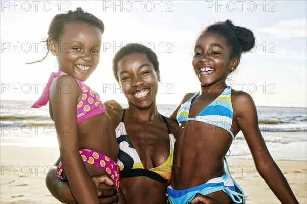 Black mother holding daughters on beach