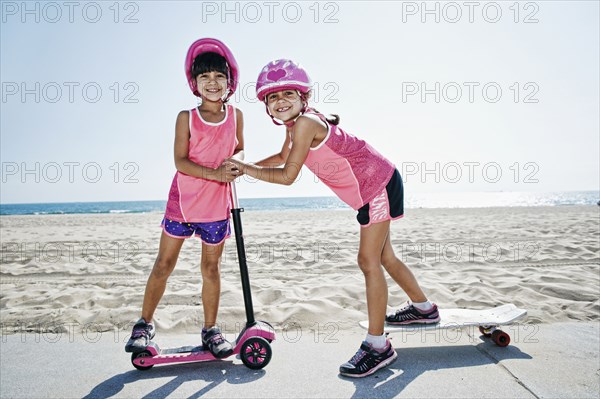 Girls playing on skateboard at scooter at beach