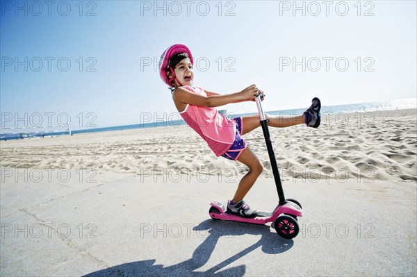 Girl riding scooter at beach