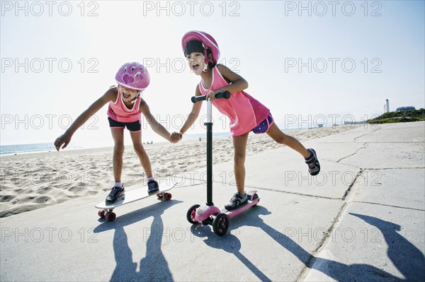 Girls riding skateboard and scooter at beach