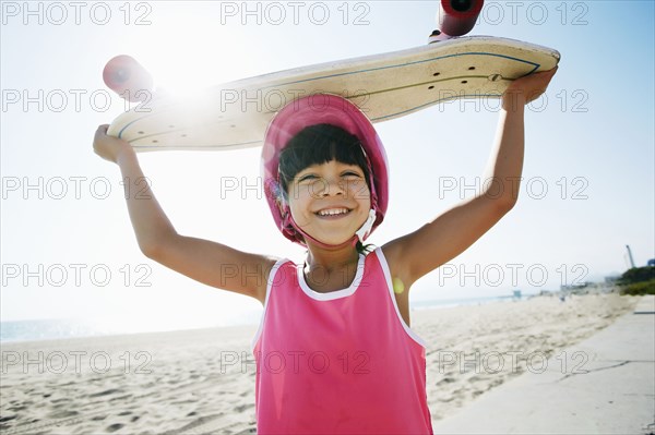 Mixed race girl holding skateboard at beach