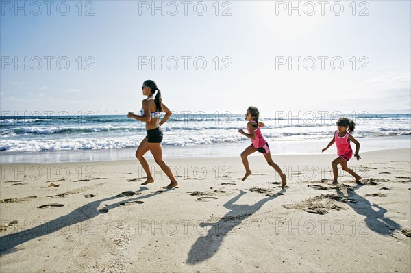 Mother and daughters running at beach