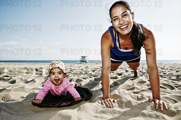 Mother and daughter doing push-ups at beach